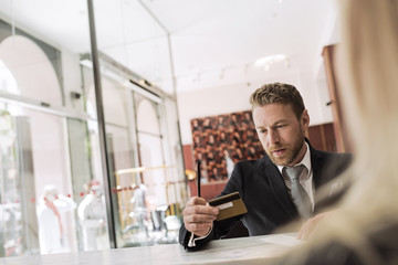 Businessman looking at credit card in hotel reception