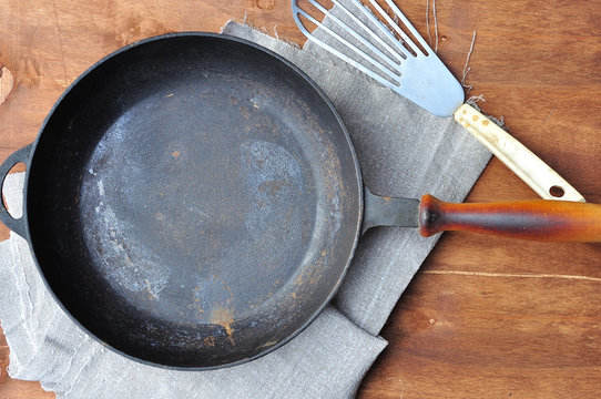 Empty black cast-iron frying pan and iron spatula on the table