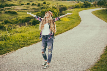 Fototapeta premium Beautiful young woman enjoys walking at the country road.