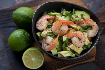 Avocado salad with roasted tiger shrimps, cucumber and fresh basil, elevated view, closeup