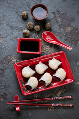 Steamed prawn hargows with soy sauce and green tea on a dark stone background, high angle view