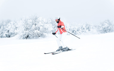 Woman skier skiing downhill on ski piste
