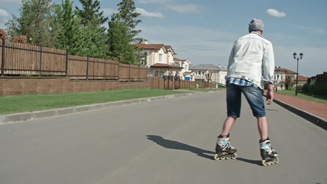 Follow shot, rear view of senior hipster practicing roller skating on road in slow motion