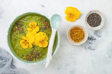 Breakfast detox green smoothie bowl topped with superfoods, chia seeds, bee pollen and edible...