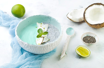 Vegan blue spirulina smoothie and chia pudding bowl topped with coconut flakes and lime zest