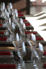 Sun light illuminates a wooden table full of empty glasses and white candles