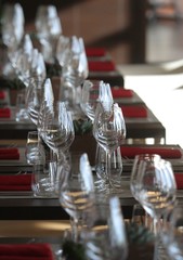 Sun light illuminates a wooden table full of empty glasses and white candles
