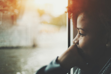 True tilt shift portrait of smiling black teenager girl near window traveling by ship, biracial...