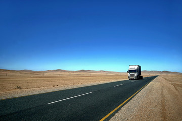 Fototapeta na wymiar Truck unterwegs auf einer Wüstenstraße