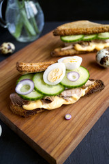 Healthy sandwich with tuna, cucumber and sauce. on a wooden Board. black background