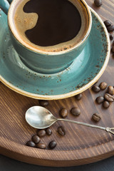 Fototapeta na wymiar Cup of black coffee with coffee beans on wooden tray.