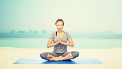 Fototapeta na wymiar woman making yoga meditation in lotus pose on mat