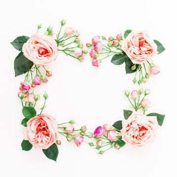 Frame made of purple roses, leaves and pink buds on white background. Flat lay, top view. Floral composition of pink flowers