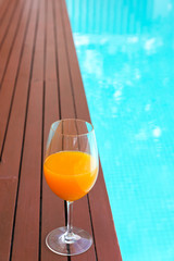 orange juice in wine glass on edge  the blue sky pool in party luxury hotel, thailand