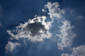 幻想風景・青空と雲に隠れた太陽「空想・雲のモンスター（現れ始めた黒いモンスターに向かって、口を大きくあけて威嚇するモンスターたち（右側）のイメージ」威嚇、脅威、可能性、出現、何かが始まる予感など・周辺にキャッチコピー（案「始まりはいつも突然！」「何かが始まる予感！」「負けない力」など）