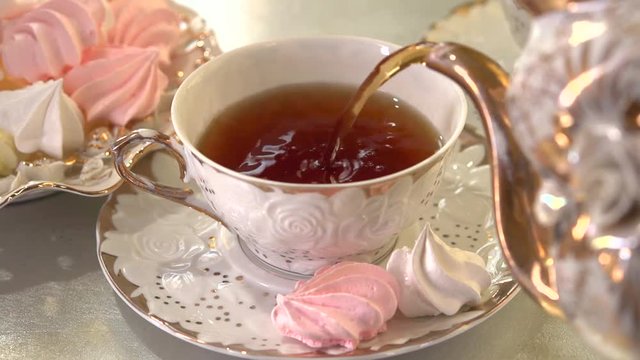 Tea Pouring. Porcelain cup of Healthy Tea closeup. Luxury dishes and interior. Slow motion video footage 240fps.