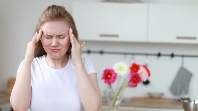 Beautiful lady has head pain in the kitchen