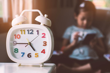 Clock and child playing smartphone.