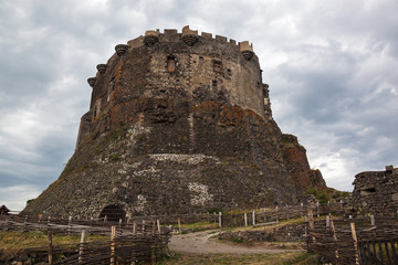 High stony walls of medieval castle Murol tower on hill on cloudy dramatic sky background in Auvergne, France