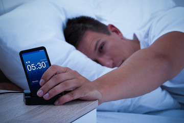 Man Waking Up With Mobile Alarm Clock