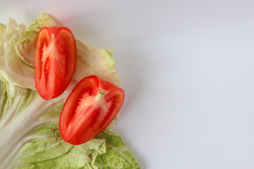 Tomato slices on a salad leaf on the white background