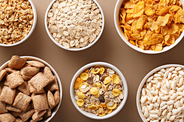 Bowls of various cereals view from above. Corn flakes, oat flakes, muesli, granola assortment. Top view