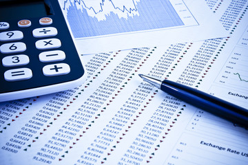 Calculator and pen with report and histogram on the desk. Picture taken in studio with soft-box.