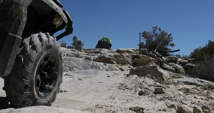 Two off road recreation ATV rock climb steep trail Utah. San Rafael Swell desert landscape. Sandstone towers, valleys, canyons, gorges, mesas. Off road all terrain 4x4 vehicle ATV.