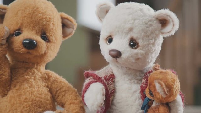 Plush bears handmade: two large teddy bears and two small ones on the table. Collectible soft toy - a teddy bear, as in the 20th century. A toy in vintage style is handmade. Old-fashioned teddy bears