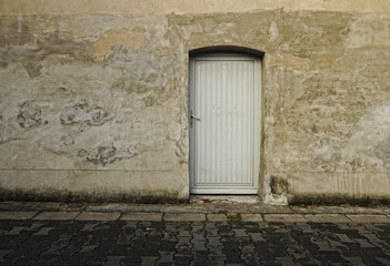 Fototapeta na wymiar Graue Mauer mit Tür auf dem Land