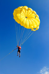 Skydiver on yellow parachute in sunny blue sky. Active lifestyle. Extreme sport.