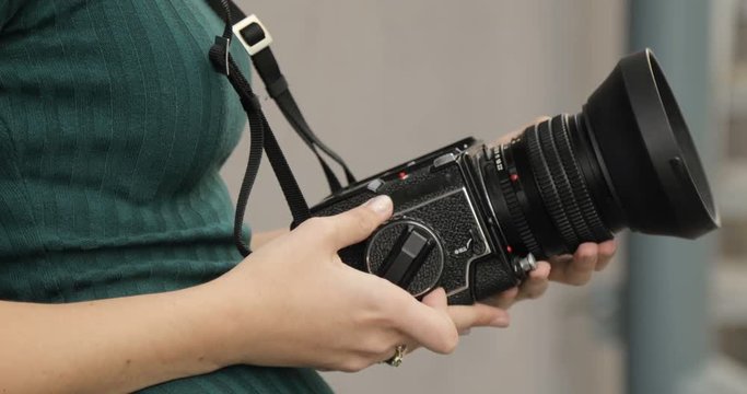 Old medium format camera in the hands of a hipster girl, close-up, film camera