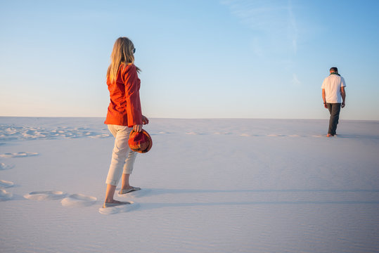 Man and a young beautiful woman go one by one in the desert