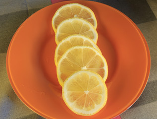 Slices of fresh lemon on an orange dish