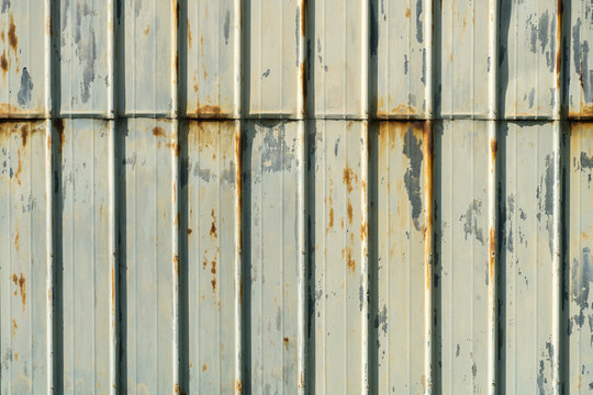 verwitterte und rostige Metallfassade eines Geb&auml;udes mit abgebl&auml;tterter wei&szlig;er Farbe