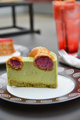piece of pistachio cake with profiteroles on table of street cafe
