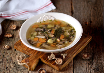 Mushroom soup with potatoes, carrots, onions and chicken meat on an old wooden background. Rustic style.