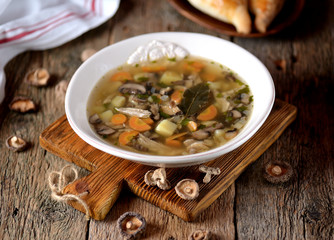 Mushroom soup with potatoes, carrots, onions and chicken meat on an old wooden background. Rustic style.