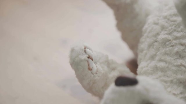 A thin brush in the hands of the artist to create soft toys - drawing details of a handmade toy. The toy is made in classic style. The process of creating a teddy bear: the master draws a toy paws.