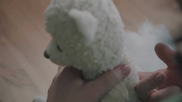 Repair of plush toys: female hands sew a teddy bear. Creating soft handmade toys. Broken toy vintage bear cub - restoration of an old toy. Sew a soft toy