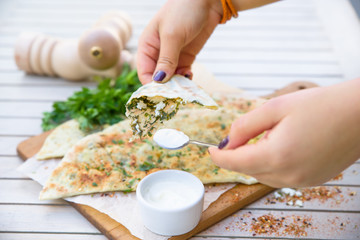 Woman eating Turkish Gozleme cake in cafe, hands in frame