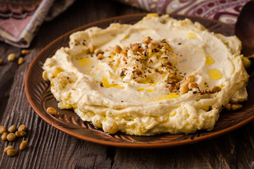 Plate of creamy hummus on wooden table.Ramadan food. Selective focus. Toned image