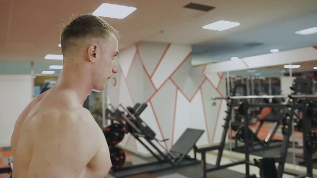 A man is training with dumbbells in the gym.