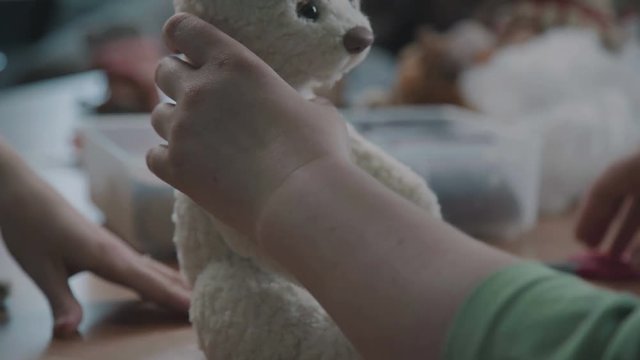 Making soft toys handmade. A broken toy is a vintage bear cub - restoring an old toy. Sew a soft toy: the seam on the back. Female hands sew a teddy bear in an old-fashioned style.