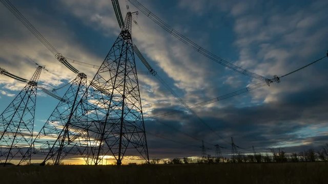 Electrical pylons against timelapse clouds at the sunset.