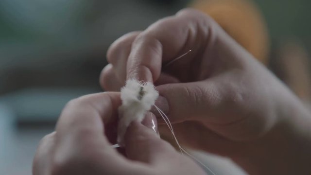 Stitching the details of a plush toy. Repair of plush toys: women's hands sew a teddy bear. Making soft toys handmade. A broken toy is a vintage bear cub - restoring an old toy.