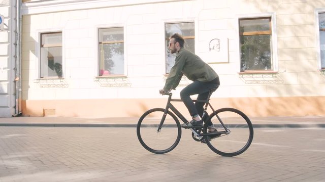 Cyclist man riding fixed gear sport bike in sunny day on a city