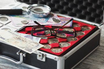 Different collector's coins in the box with a magnifying glass