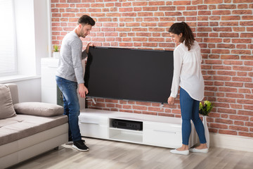 Couple Holding Television At Home