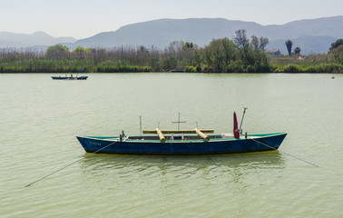 Fototapeta na wymiar Calm lake with fishing boats. Fresh water lagoon in Estany de cullera. Valencia, Spain